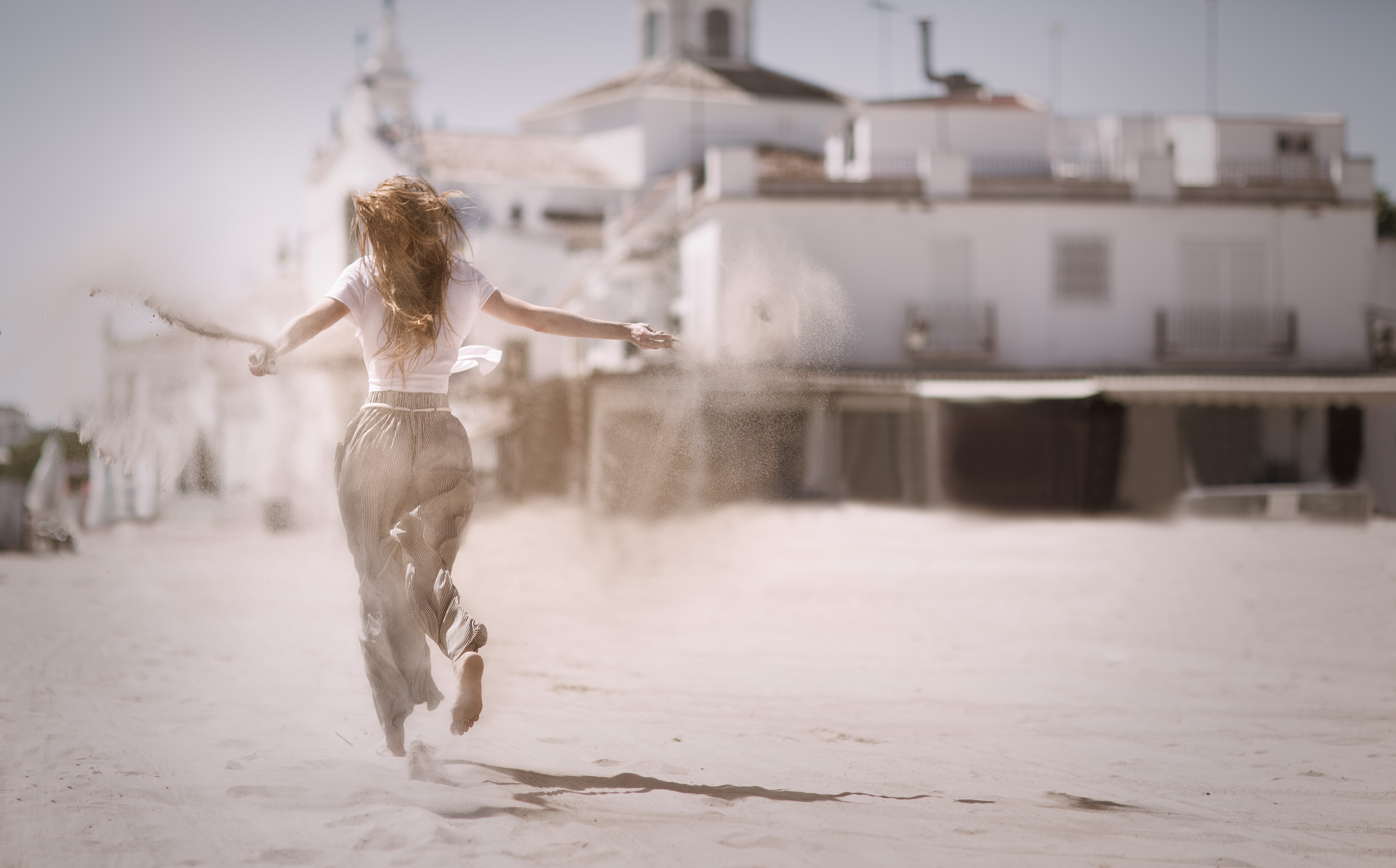 woman-running-on-sand-near-white-concrete-building-736505.jpg